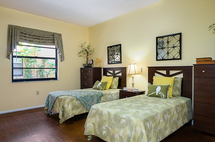 A well-decorated bedroom with two single beds, complete with matching bedspreads, wall art, and a bedside lamp.