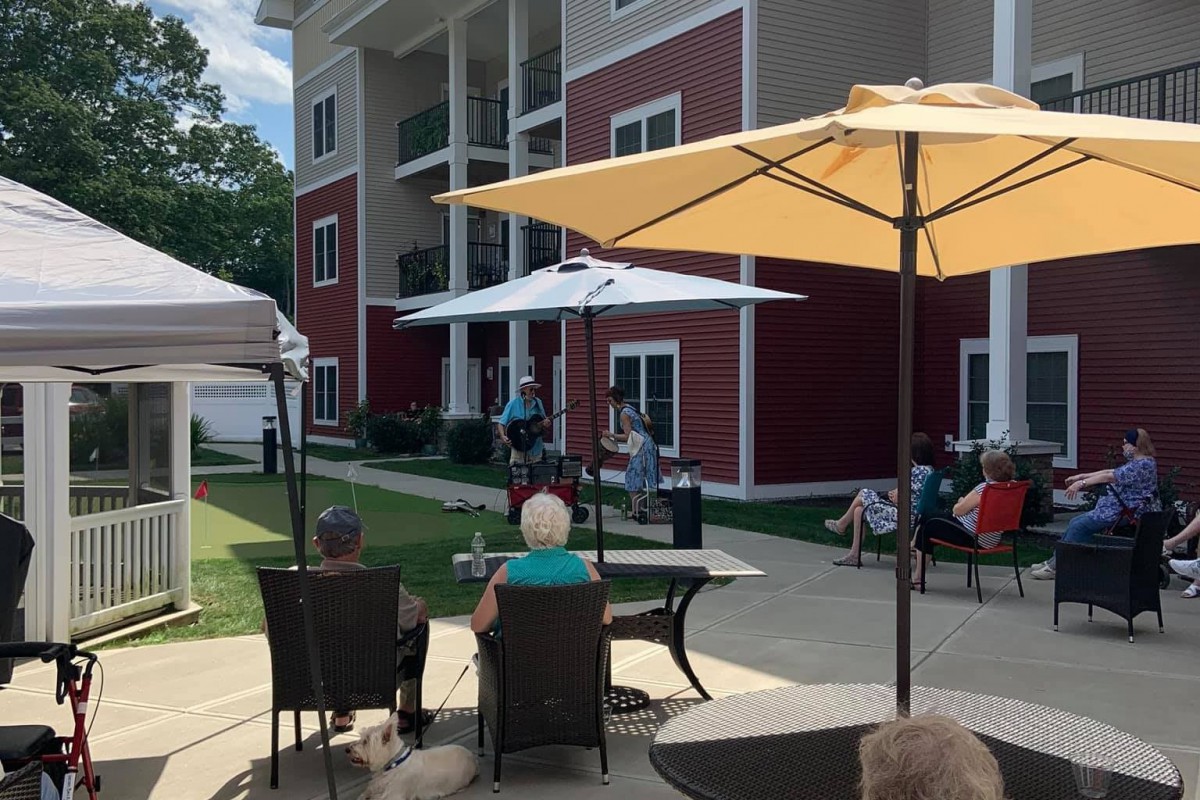 People seated outdoors enjoying a live performance beside a residential building.