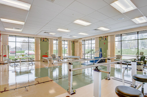 A spacious rehabilitation room equipped with therapy bars and exercise equipment, featuring ample natural light.