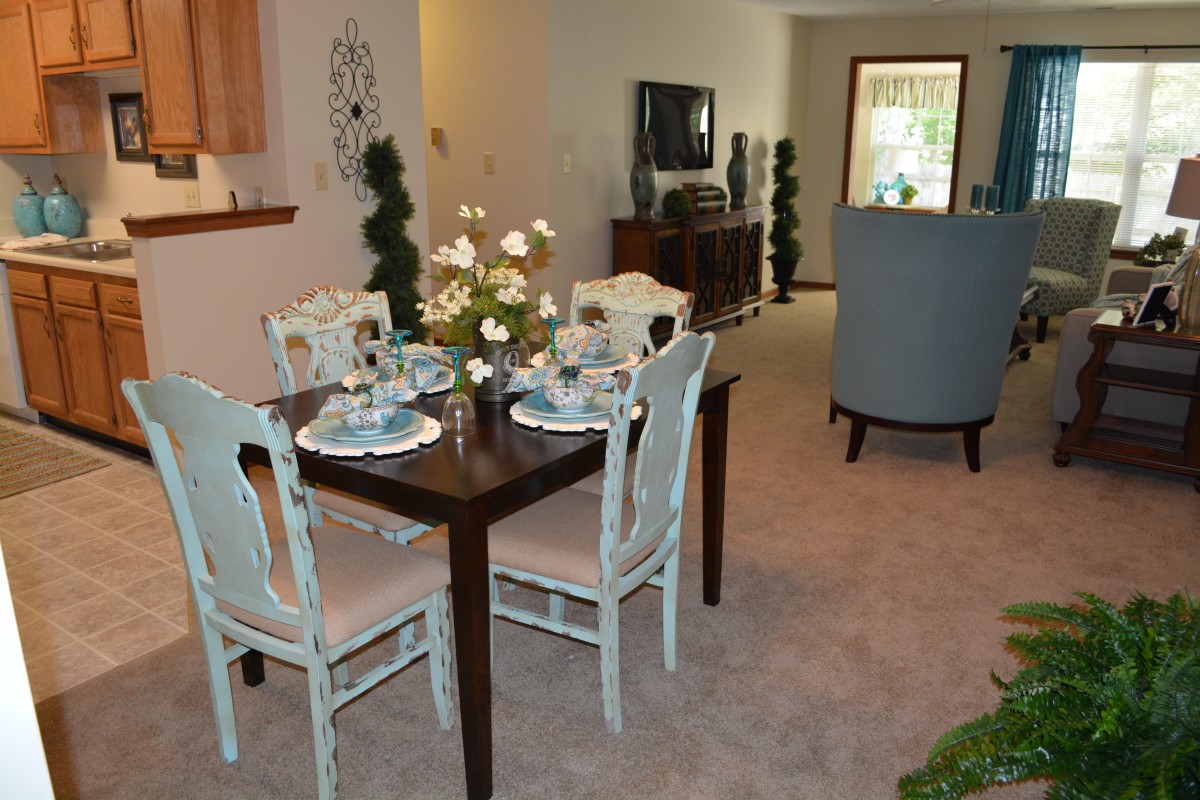 A cozy dining and living area featuring a neatly set dining table with four chairs and elegant decor.