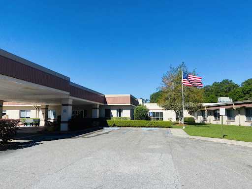 A healthcare facility with a clear blue sky and the American flag waving in front.