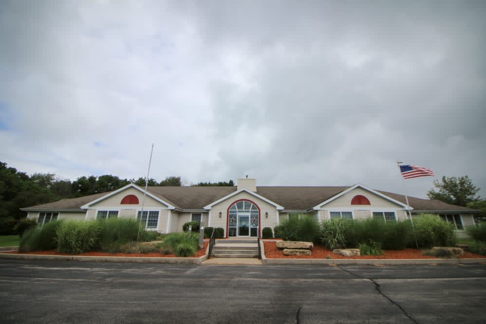 A single-story building with a cloudy sky backdrop and surrounding greenery.