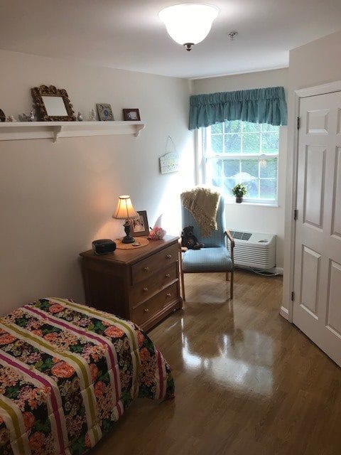 A cozy bedroom with a single bed, dresser, and a window allowing natural light to flow in.