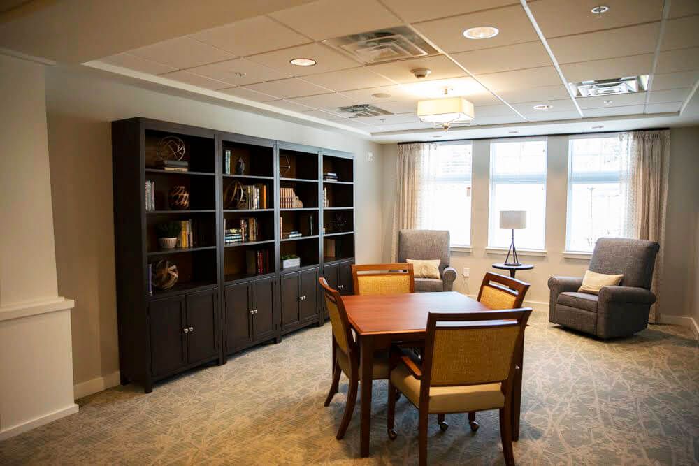 A cozy room with a bookshelf, table, and chairs.