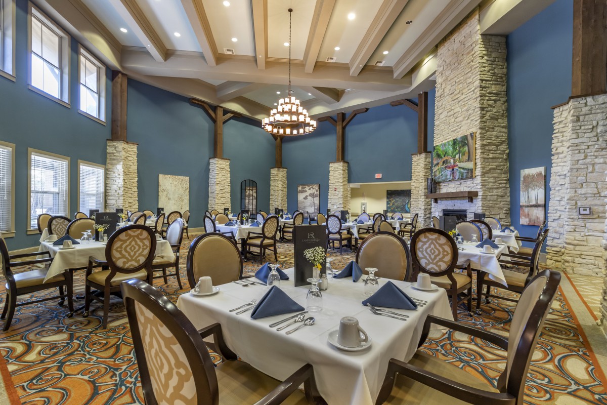 An elegant restaurant dining room with neatly arranged tables and a central chandelier.