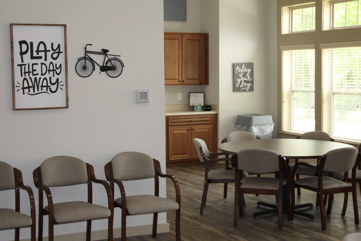 A well-lit waiting room with chairs, a table, and wall decor including a bicycle-themed artwork.