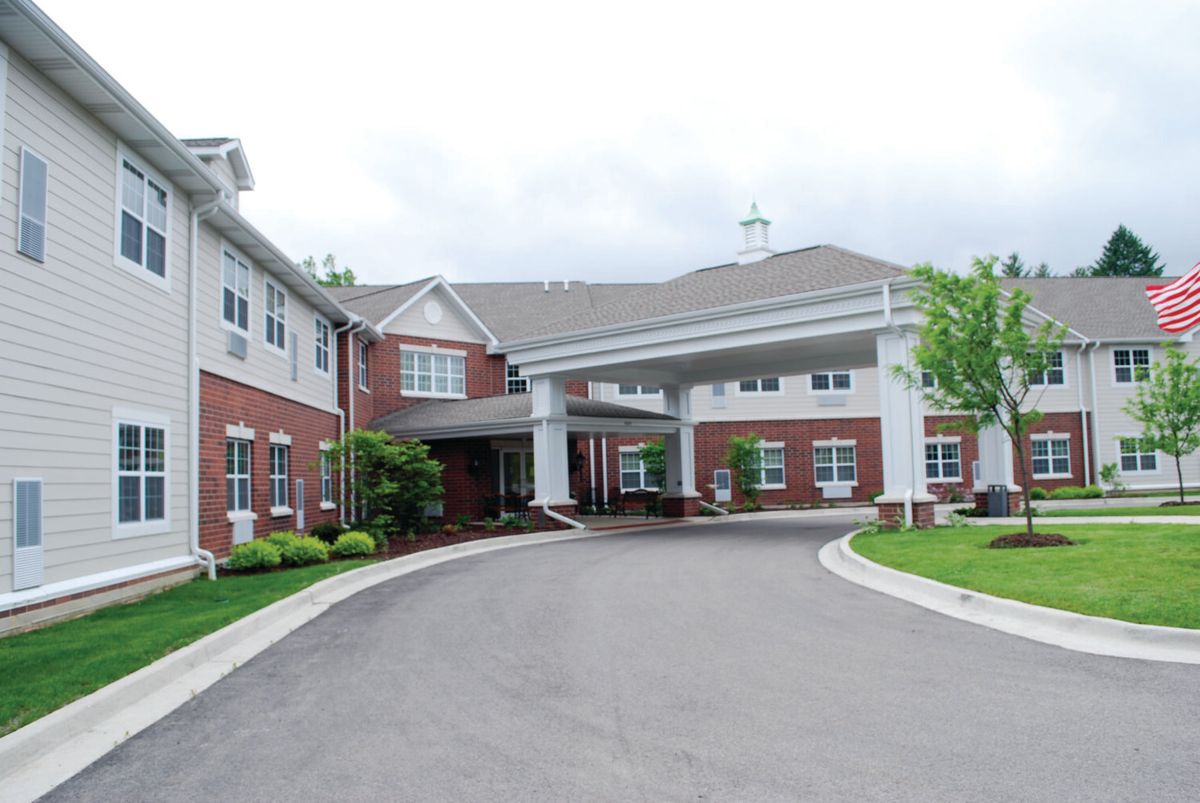 The front entrance of a large brick building with a covered driveway.