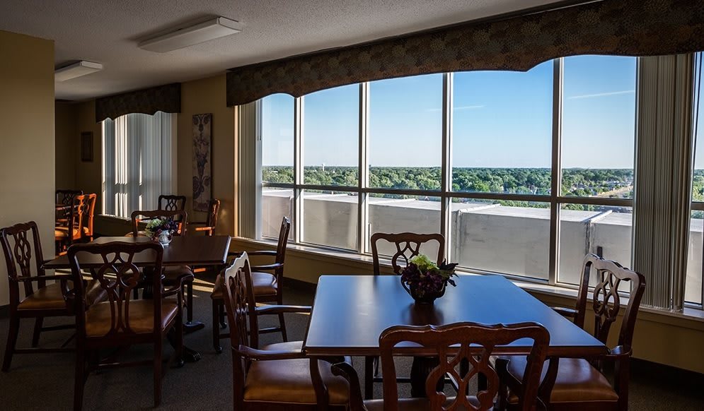 A dining area with wooden tables and chairs, featuring a large window offering a scenic view.