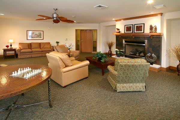 A cozy living room featuring comfortable seating, a central table, and a warm fireplace.