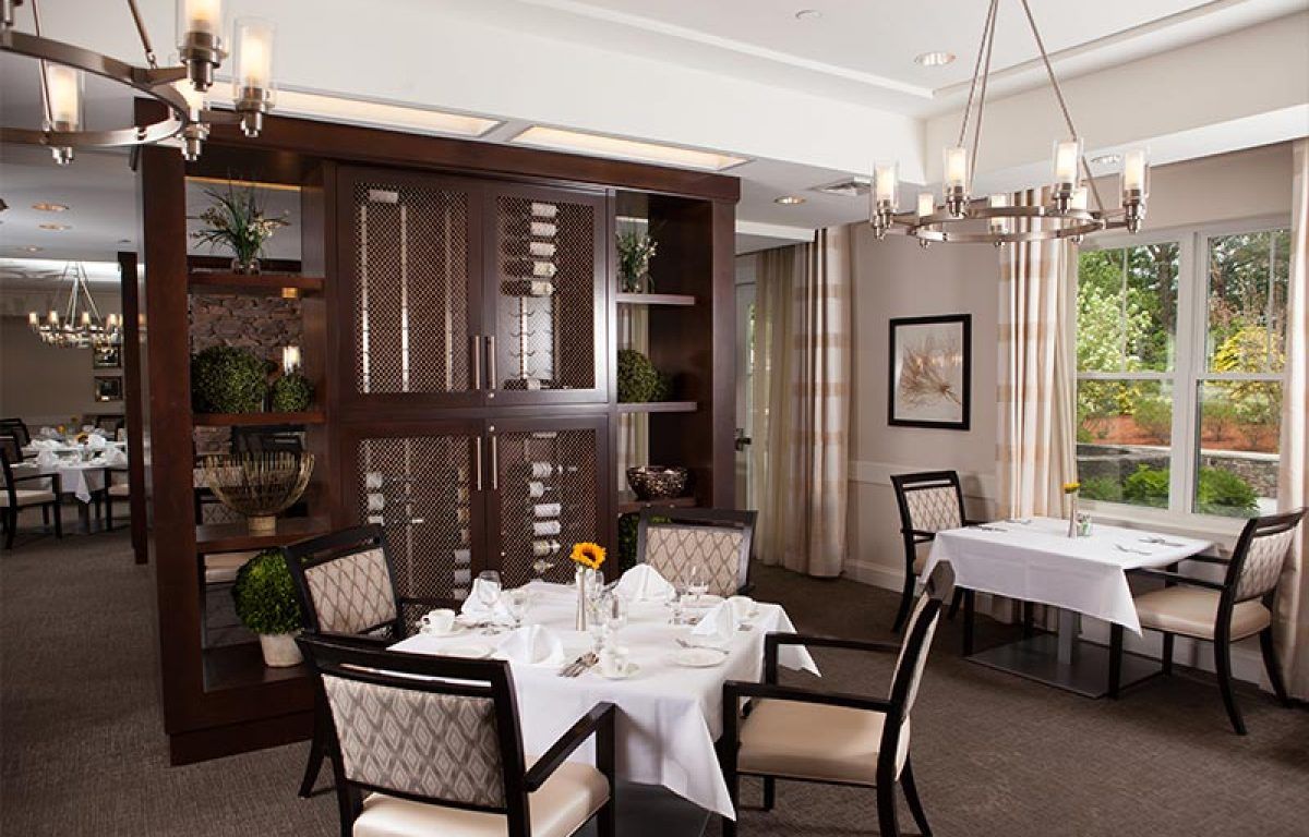 An elegant dining area with a neatly arranged table setting, complete with a chandelier overhead.