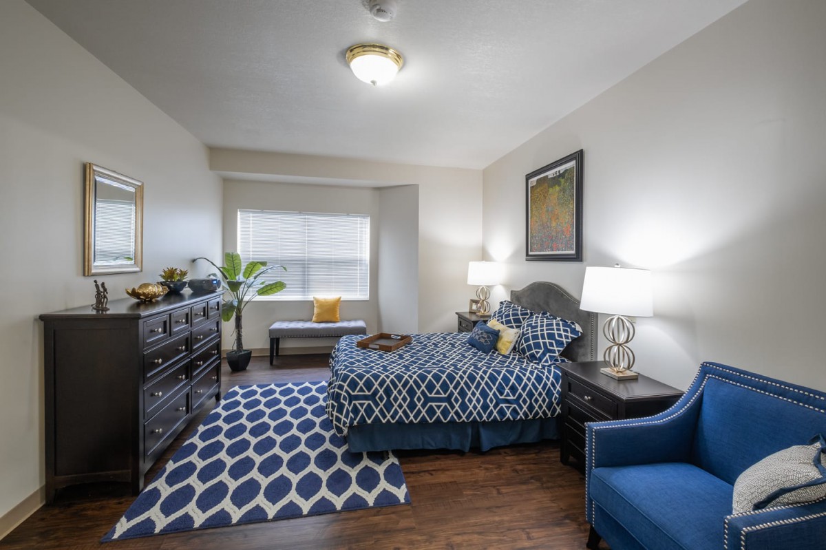 A well-decorated bedroom featuring a stylish blue and white theme with a comfortable bed, patterned rug, and elegant lamps.
