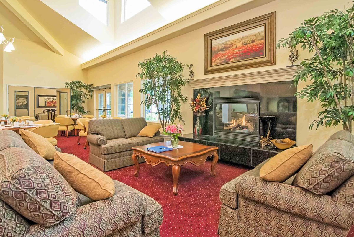 A cozy living room with plush sofas, a central coffee table, and a warm fireplace surrounded by elegant decor.