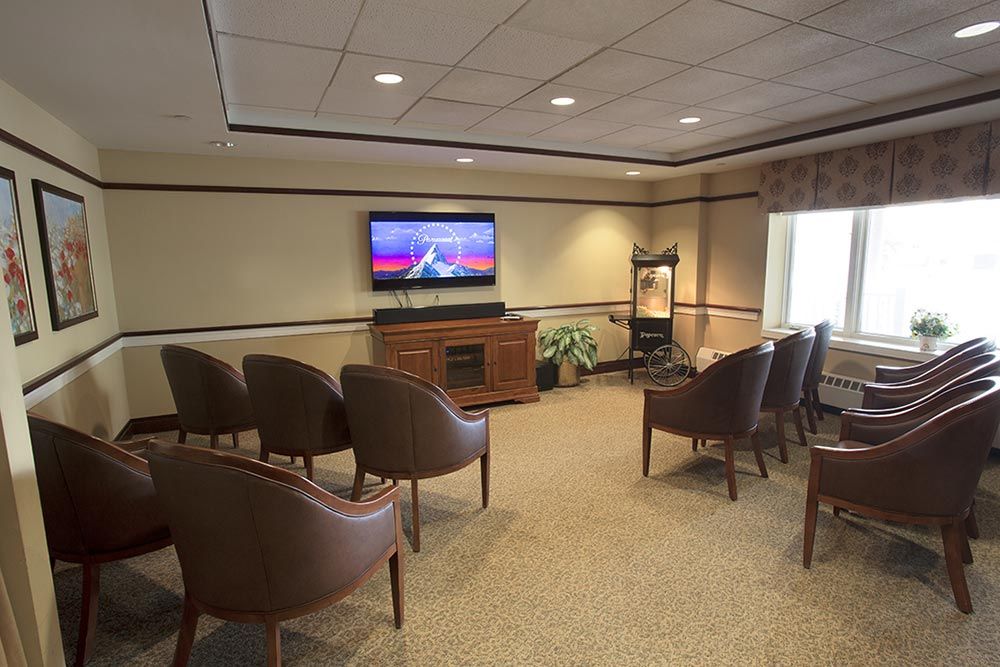 A cozy waiting room with rows of chairs facing a television on the wall.