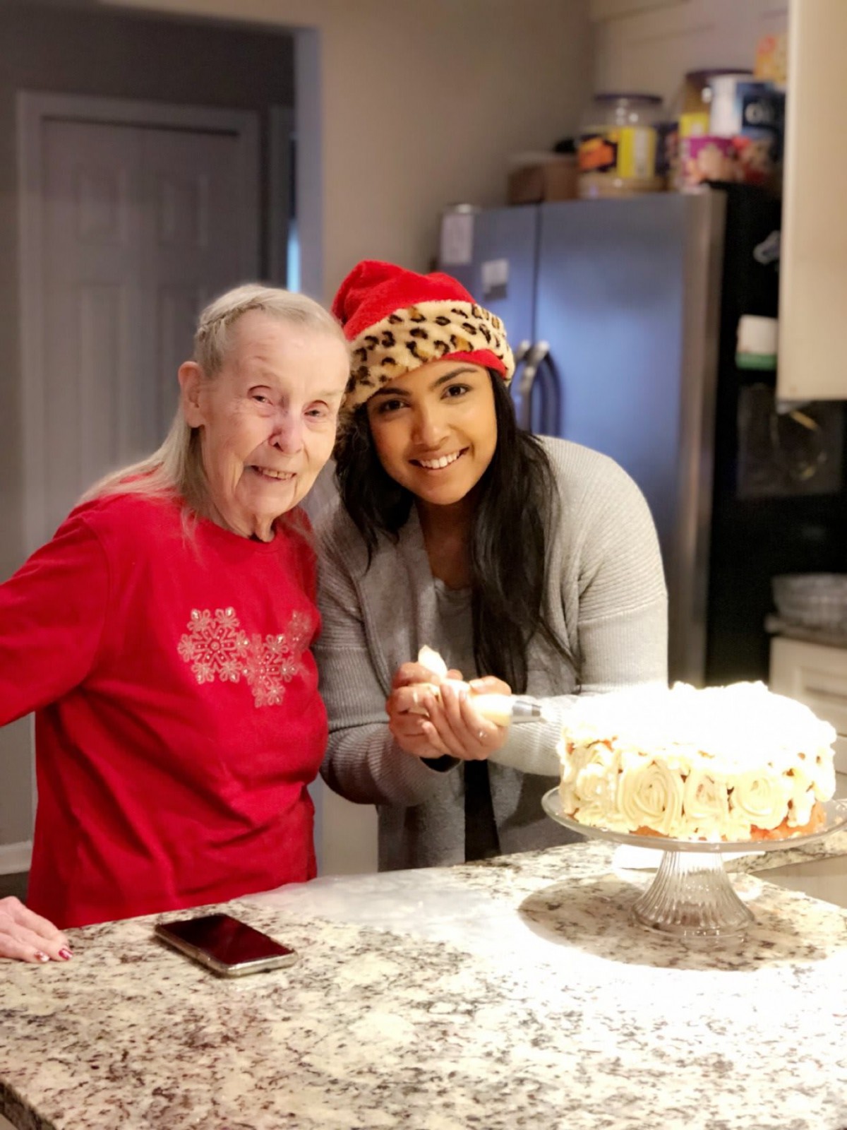 Two people enjoying a festive celebration with a cake in the kitchen.