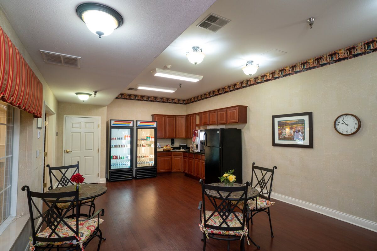 A cozy kitchen and dining area with tables, chairs, and refrigerators.
