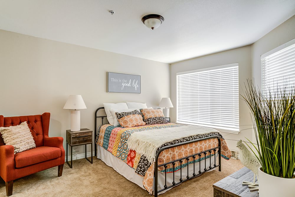 Cozy bedroom with a metal bed frame, colorful quilt, and natural light.