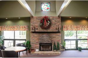 A cozy brick fireplace adorned with a festive wreath in a well-lit living room.