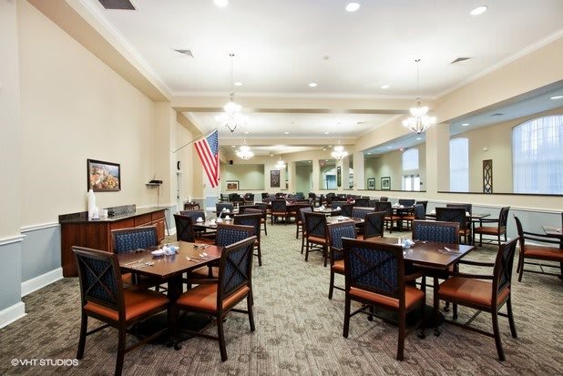 A spacious dining room with neatly arranged tables and chairs, featuring elegant lighting and decor.