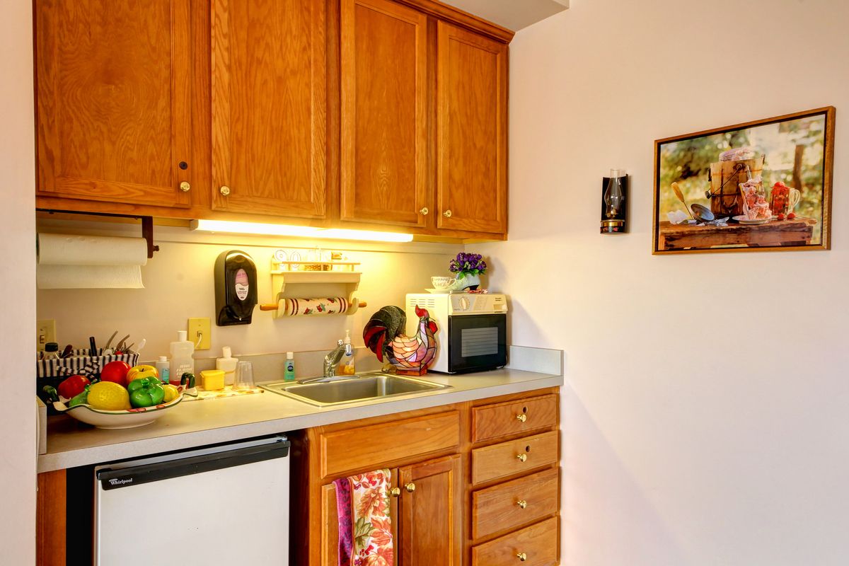 A small kitchen with wooden cabinets, a countertop, microwave, sink, and dishwasher.