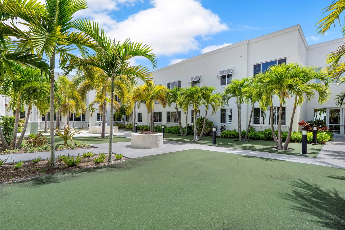 A modern building with palm trees in a courtyard under a blue sky.