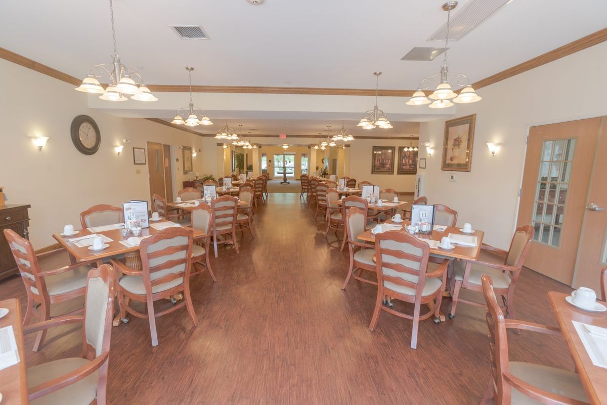 An empty dining area with neatly arranged tables and chairs, well-lit by overhead lights.