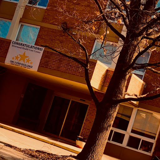 A modern building with a prominent sign and a bare tree in front.