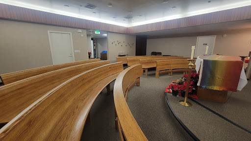 A serene interior view of a chapel featuring curved wooden benches and softly lit ambiance.