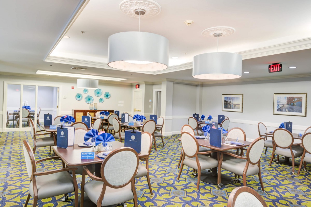 A modern restaurant dining area with neatly arranged tables and chairs, featuring stylish lighting fixtures and contemporary decor.