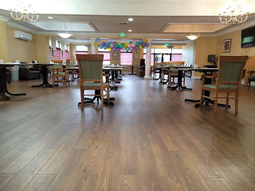 A spacious community room with wooden floors and seating arrangements, decorated for an event.