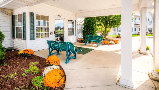 A welcoming patio entrance with benches and vibrant floral landscaping.