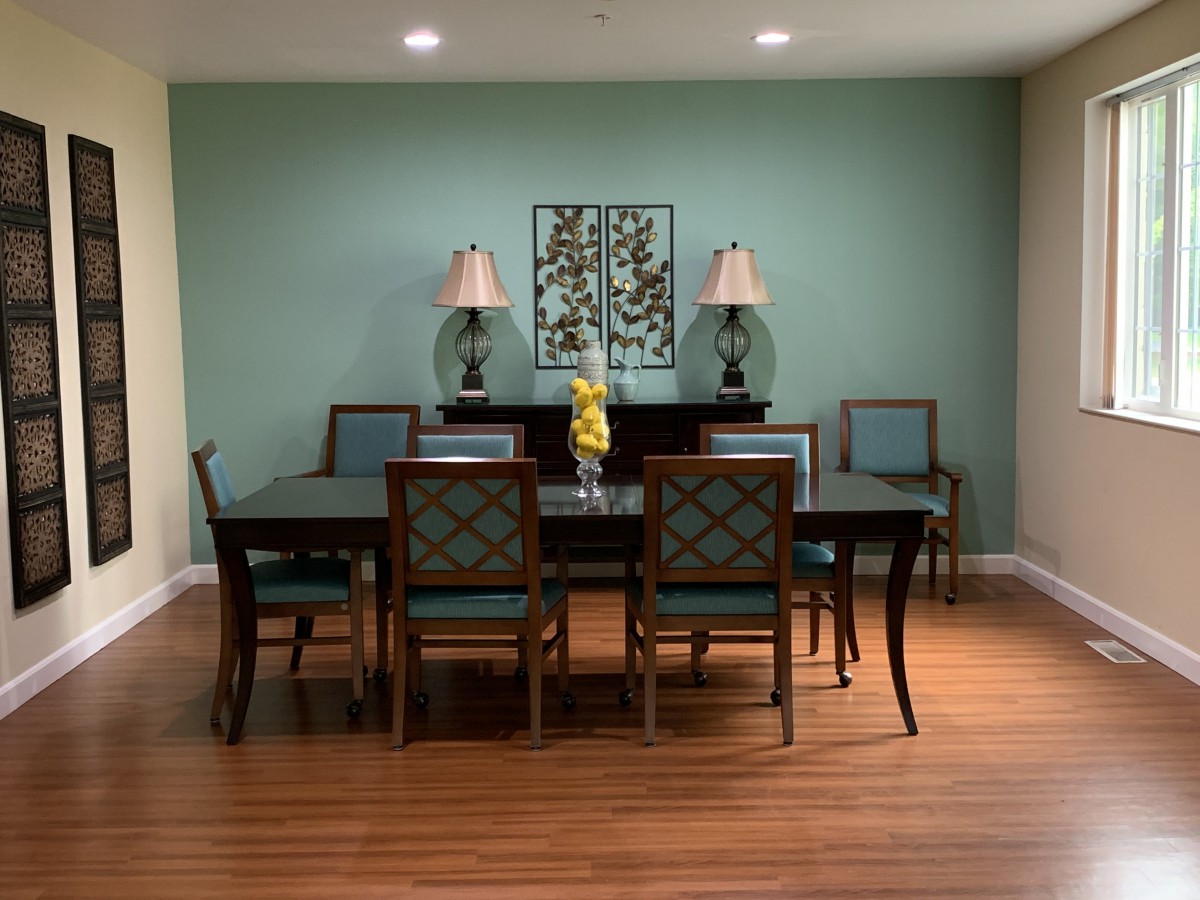 A well-decorated dining room with a large table, chairs, lamps, and wall art.