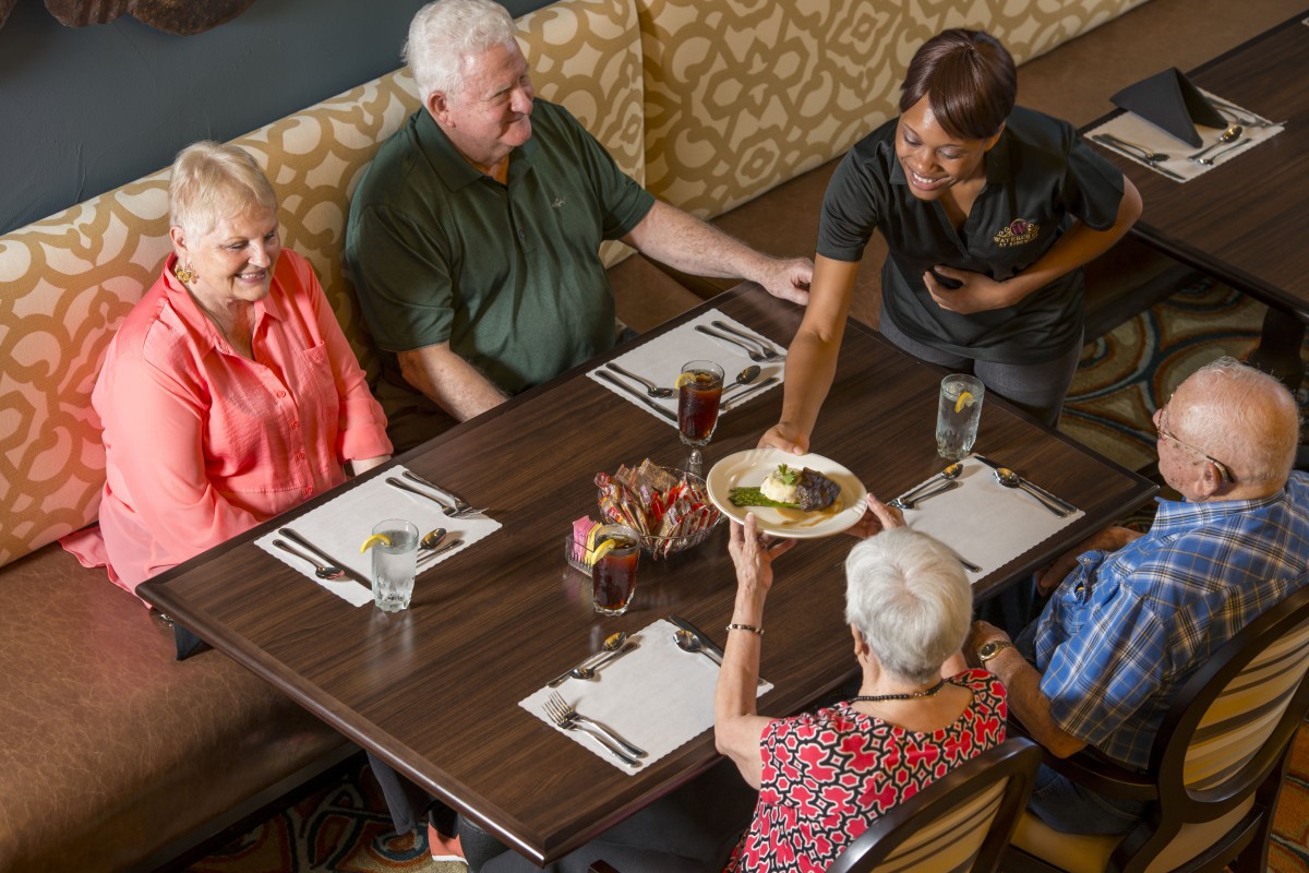 A server delivers a dish to a group of people dining at a restaurant.