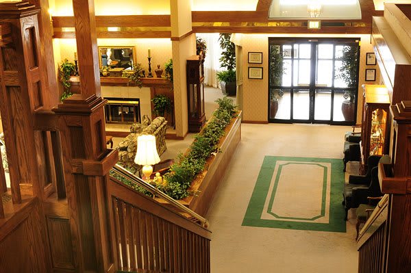 A cozy lobby interior with a wooden staircase, decorative plants, and comfortable seating.