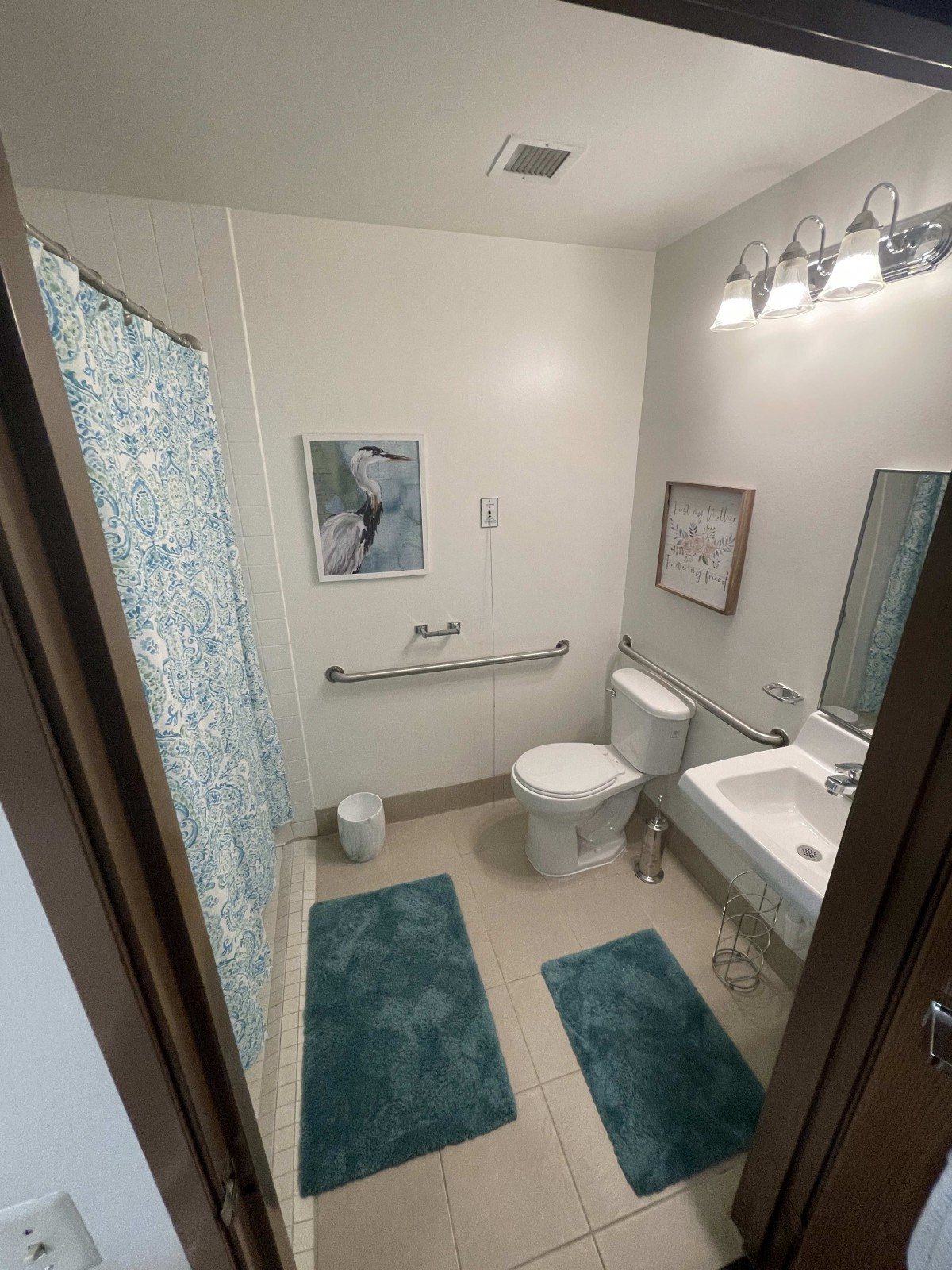 A modern bathroom with teal accents, featuring a toilet, sink, and decorative elements.
