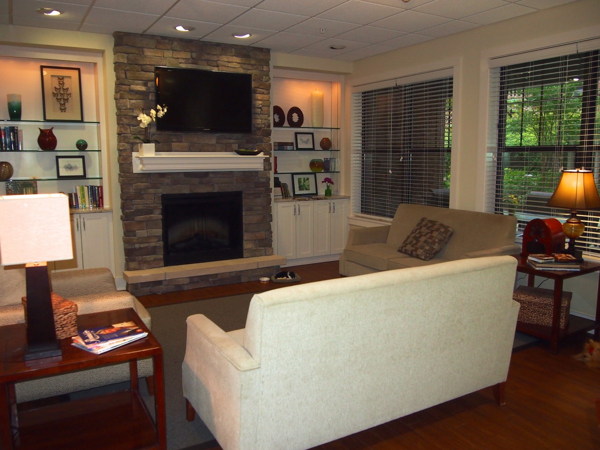A cozy living room featuring a stone fireplace and mounted television, surrounded by comfortable seating and elegant decor.