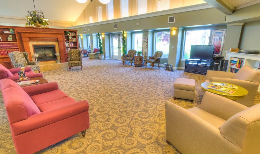 A spacious and comfortable lobby area with various seating options, decorative carpeting, large windows, and a television.