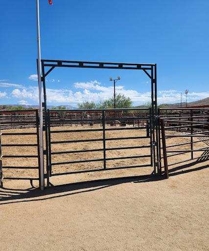 An open gate leading into a corral under a clear blue sky.