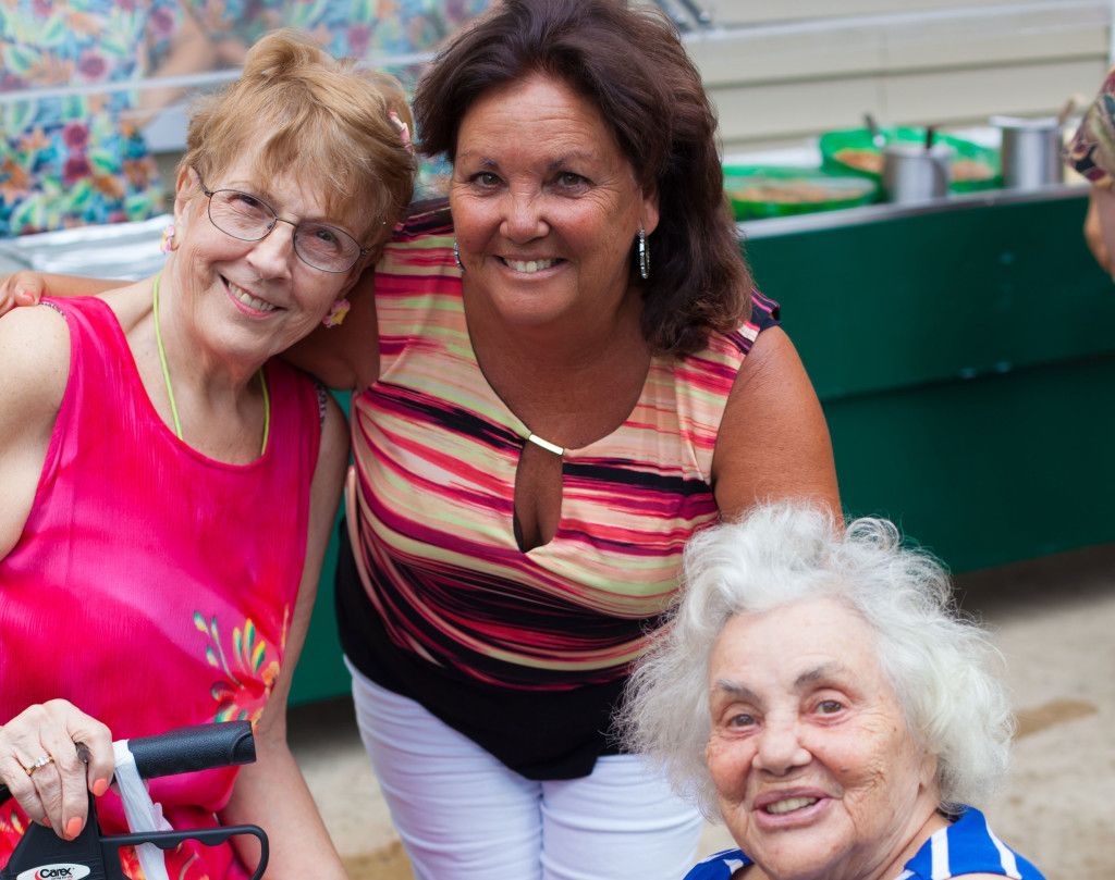 A group of three women smiling together outdoors.