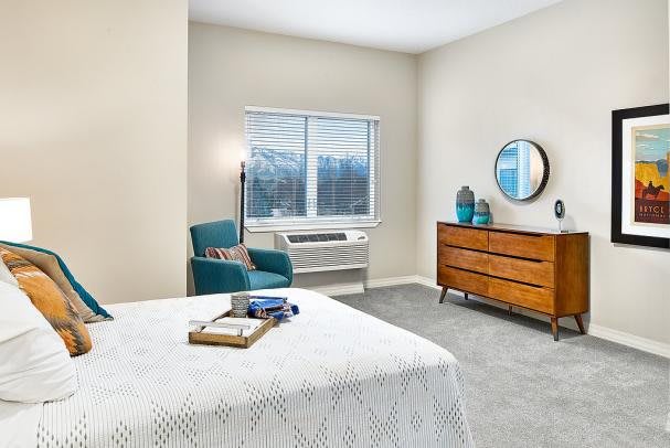 A cozy bedroom with modern furniture and a large window overlooking the outside.