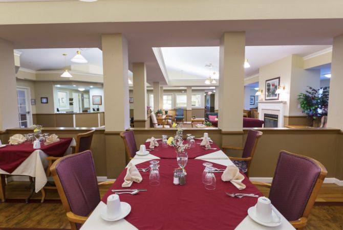 An elegantly set dining room with red tablecloths and neatly arranged napkins and glasses.
