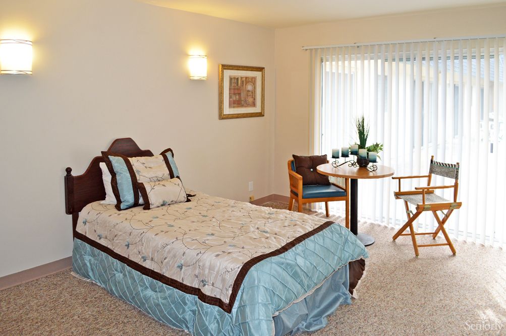 A cozy bedroom with a single bed and a small dining area.