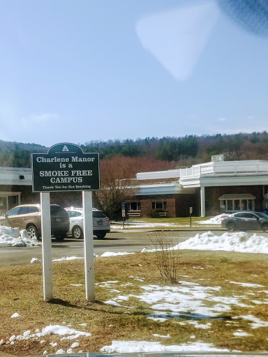 A sign for a healthcare facility with a backdrop of mountains and some lingering snow.