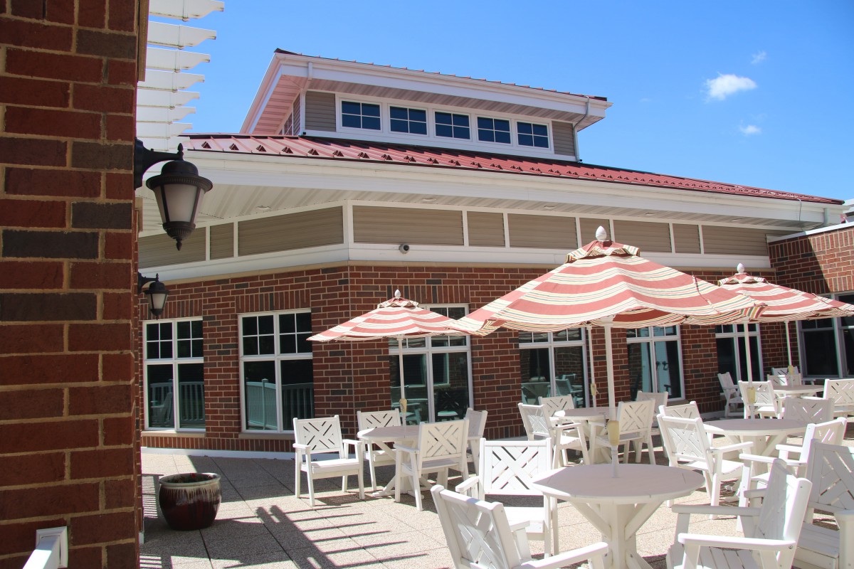 An outdoor patio with tables, chairs, and striped umbrellas on a sunny day.