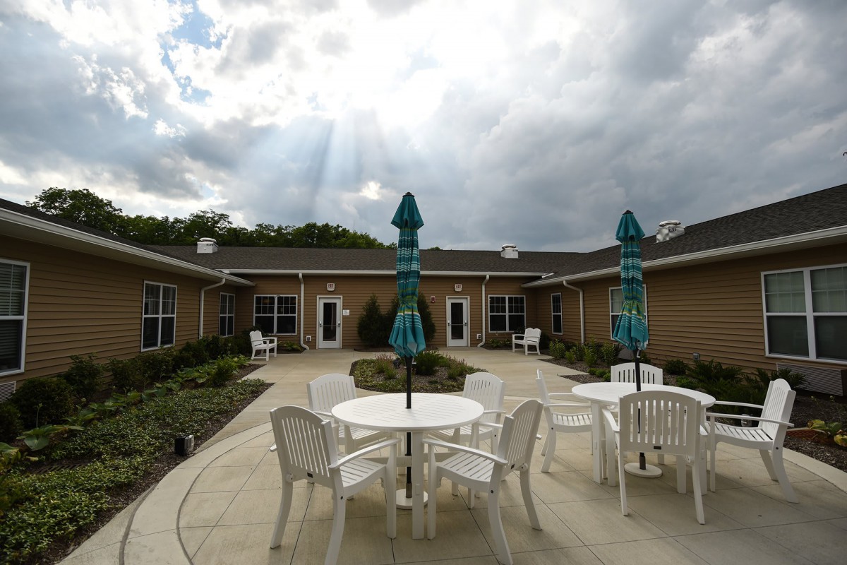 A tranquil courtyard with tables and chairs under a cloudy sky.