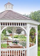 A charming wooden gazebo in a lush garden setting.