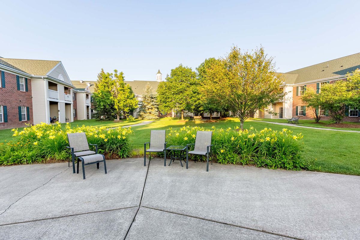 A serene outdoor patio area with chairs overlooking a lush garden and surrounding buildings.