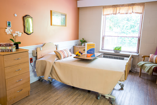 A well-lit and inviting hospital patient room featuring a bed, bedside table, and a window.