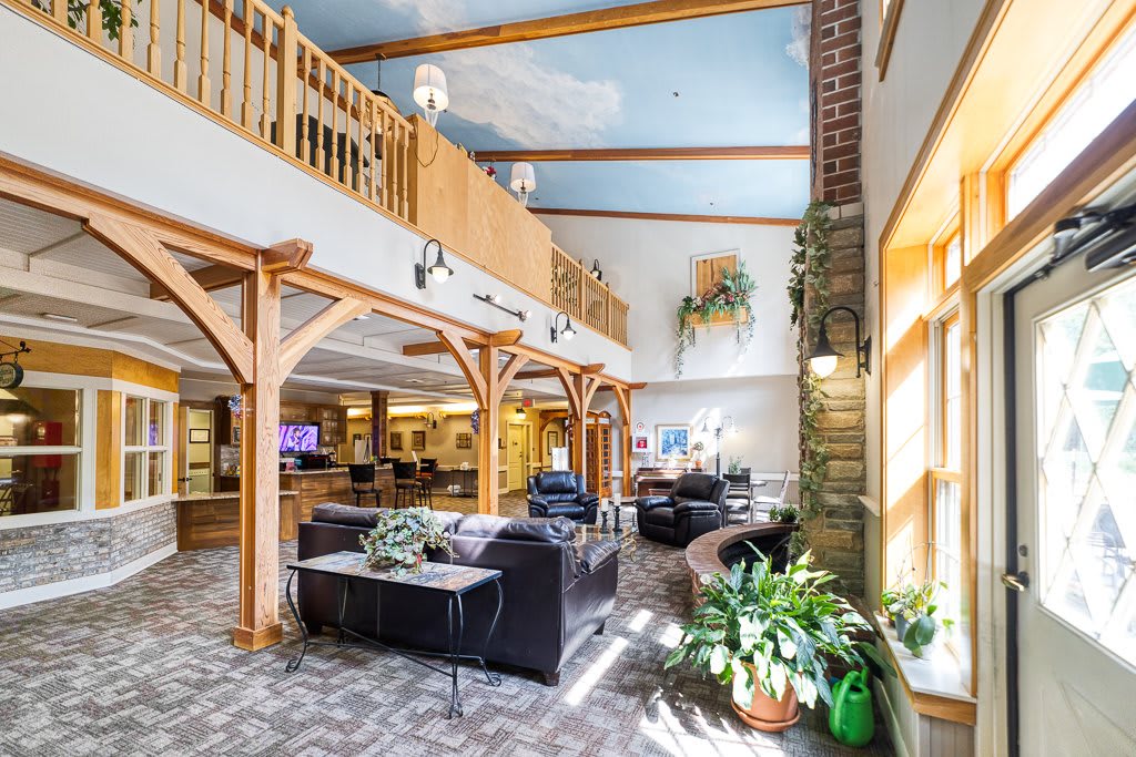 A spacious library interior featuring comfortable seating, wooden beams, and lush greenery.