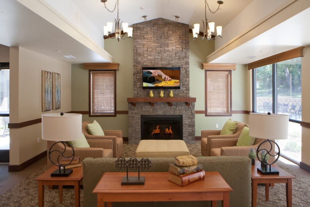 A cozy living room featuring a central fireplace, comfortable sofas, and a TV above the mantel.