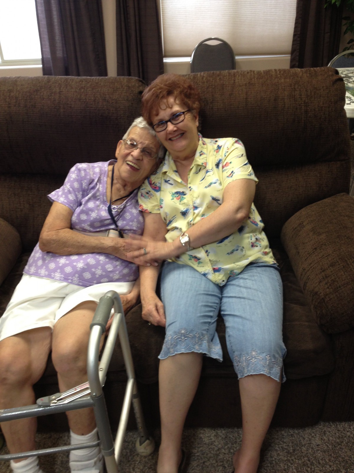 Two women sitting together on a sofa, sharing a warm moment of companionship.